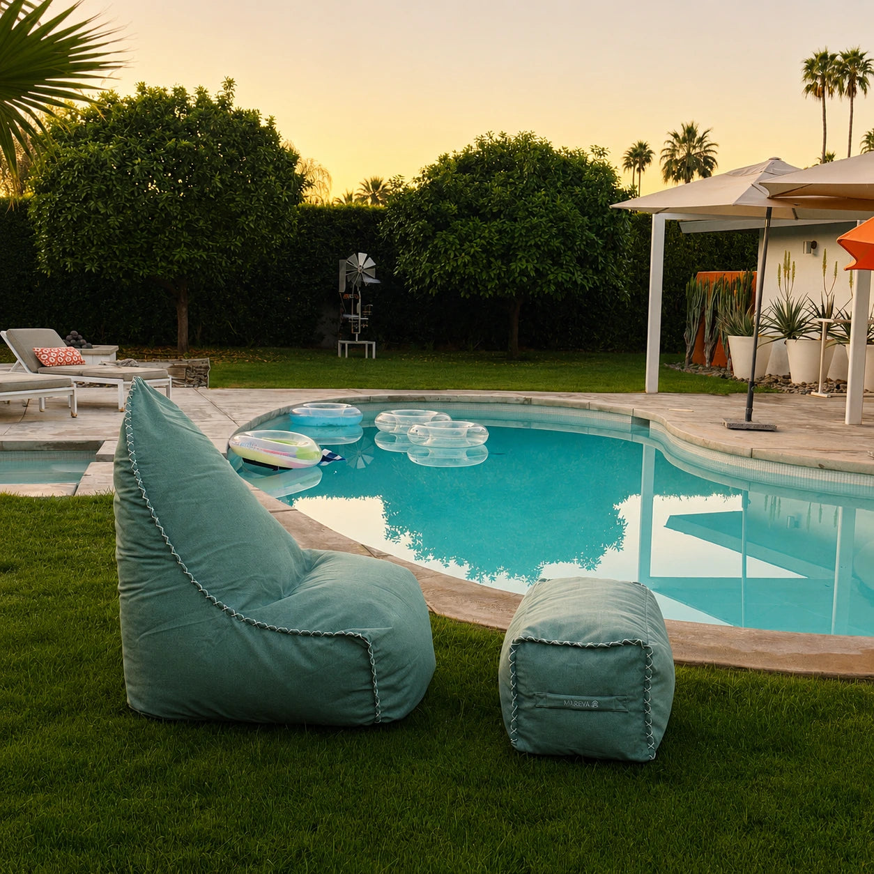 Coastal Sage MARÉVA Lounger and footrest by a pool with palm trees in the background