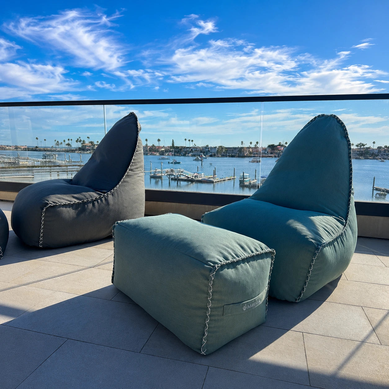 Coastal Sage Lounger and footrest set on a balcony with a view of Newport Harbor.